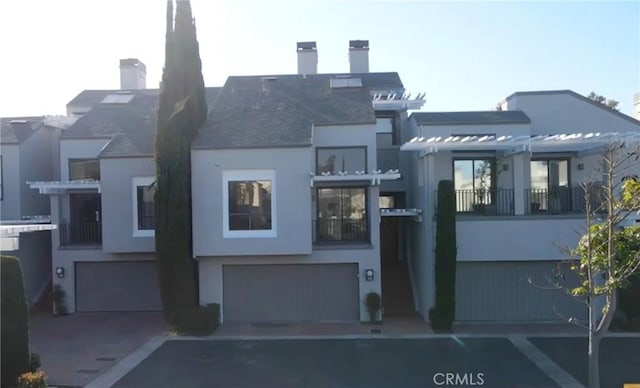 view of front facade featuring a chimney, stucco siding, and a garage