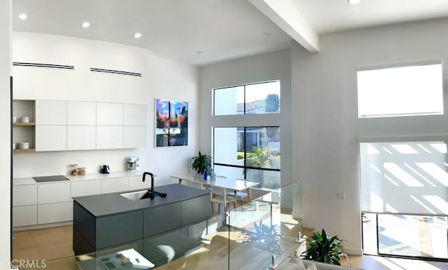 kitchen with white cabinets, modern cabinets, a towering ceiling, and a sink