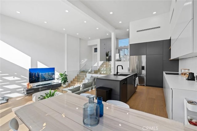 kitchen featuring light wood finished floors, modern cabinets, a sink, and stainless steel refrigerator with ice dispenser