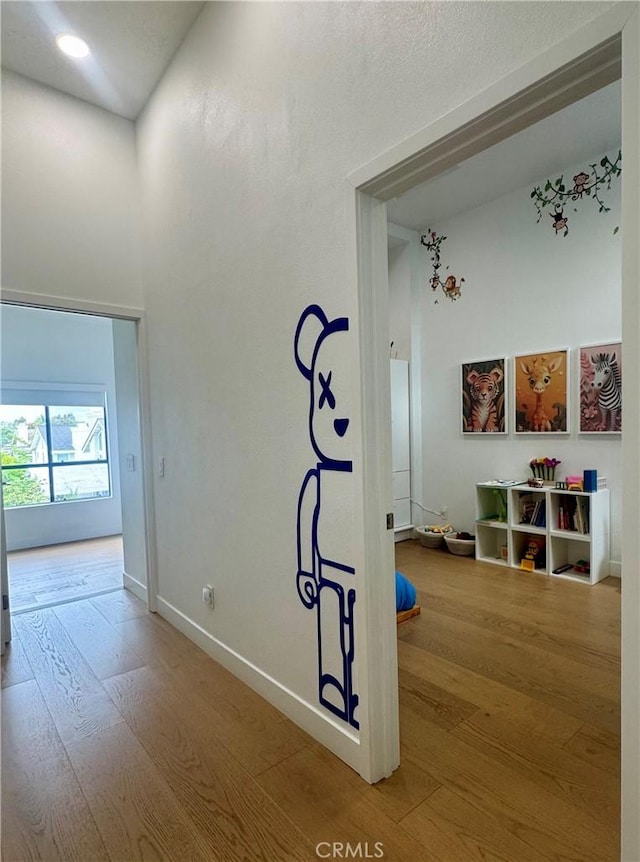 hall featuring baseboards, a high ceiling, and wood finished floors
