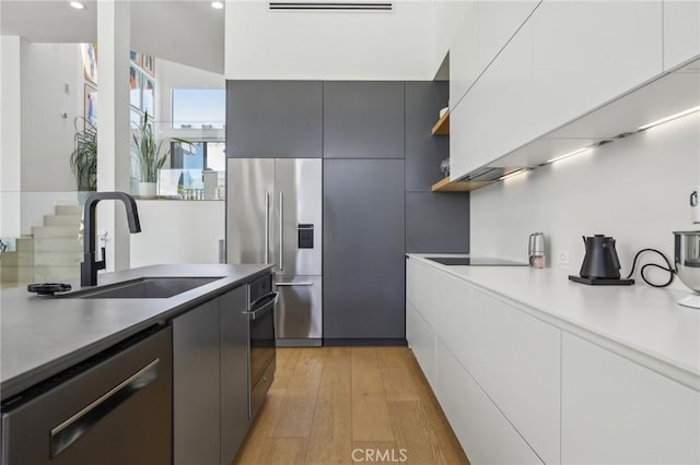 15 Waterway Unit 11, Irvine, CA 92614 - kitchen with stainless steel appliances, a sink, modern cabinets, light wood-style flooring, and white cabinetry