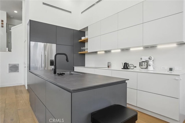 15 Waterway Unit 11, Irvine, CA 92614 - kitchen featuring modern cabinets, a sink, open shelves, stainless steel fridge, and white cabinetry