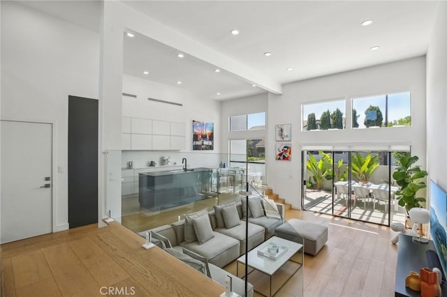 15 Waterway Unit 11, Irvine, CA 92614 - living room with a high ceiling, recessed lighting, light wood-style flooring, and beamed ceiling