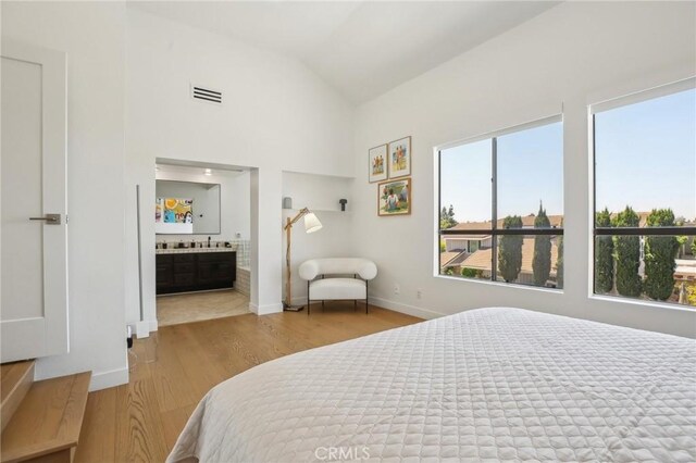 15 Waterway Unit 11, Irvine, CA 92614 - bedroom featuring wood finished floors, vaulted ceiling, ensuite bath, and baseboards