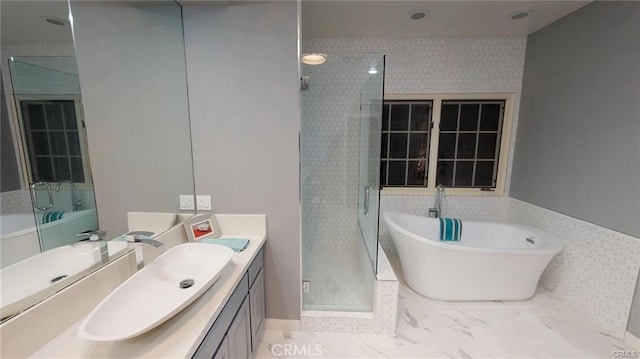 bathroom featuring vanity, a shower stall, a freestanding bath, and baseboards