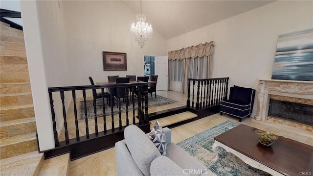 living area featuring stairs, an inviting chandelier, high vaulted ceiling, and a fireplace