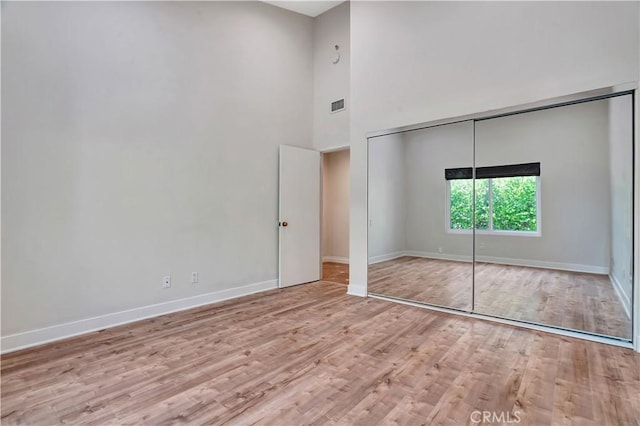 unfurnished bedroom with visible vents, baseboards, wood finished floors, and a closet