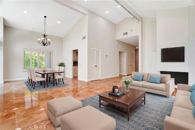 living area with an inviting chandelier, rail lighting, high vaulted ceiling, and visible vents