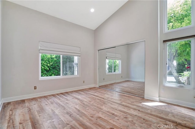 empty room with baseboards, wood finished floors, and high vaulted ceiling