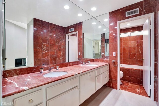 bathroom featuring tile walls, visible vents, and a sink