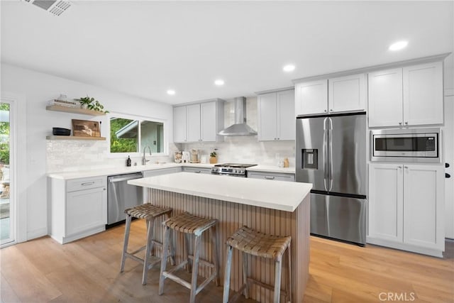 4421 Hempstead St, Simi Valley, CA 93063 - kitchen featuring stainless steel appliances, wall chimney range hood, a breakfast bar area, tasteful backsplash, and light wood-type flooring