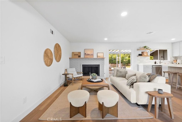 living area featuring recessed lighting, visible vents, light wood-style floors, baseboards, and a fireplace