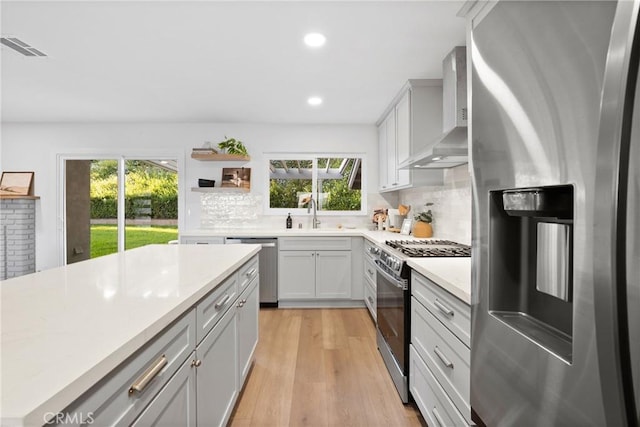 4421 Hempstead St, Simi Valley, CA 93063 - kitchen with stainless steel appliances, wall chimney exhaust hood, light countertops, backsplash, and light wood-style flooring