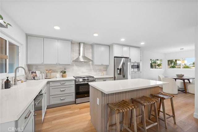 4421 Hempstead St, Simi Valley, CA 93063 - kitchen with wall chimney range hood, appliances with stainless steel finishes, a sink, a breakfast bar, and gray cabinetry