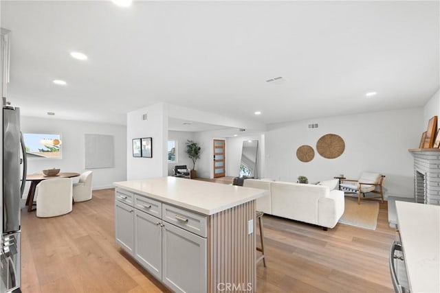 kitchen featuring a breakfast bar area, open floor plan, light wood-style floors, and a fireplace