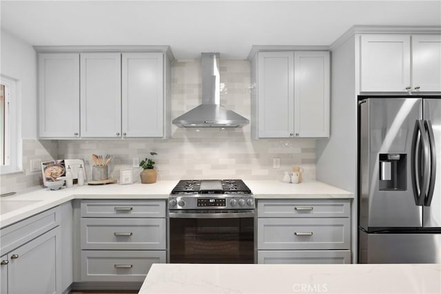 kitchen with backsplash, wall chimney range hood, appliances with stainless steel finishes, and gray cabinetry