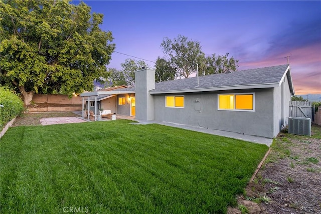 rear view of property featuring a patio area, a chimney, central air condition unit, a fenced backyard, and a yard