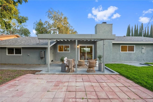 back of property with a patio area, a lawn, a chimney, and stucco siding
