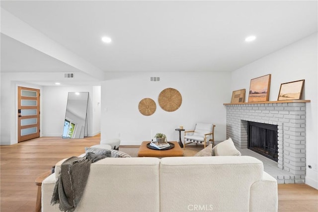 living area with recessed lighting, light wood finished floors, visible vents, and a fireplace