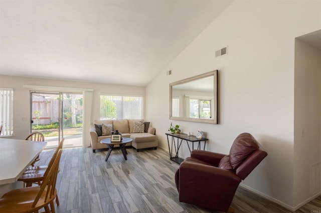 living room with visible vents, baseboards, wood finished floors, and high vaulted ceiling