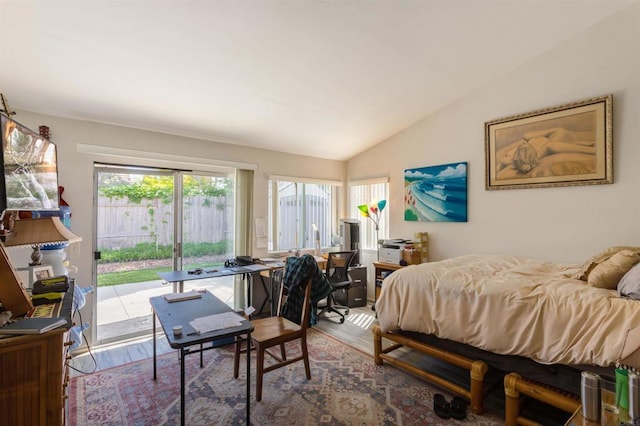 bedroom with vaulted ceiling, wood finished floors, and access to exterior