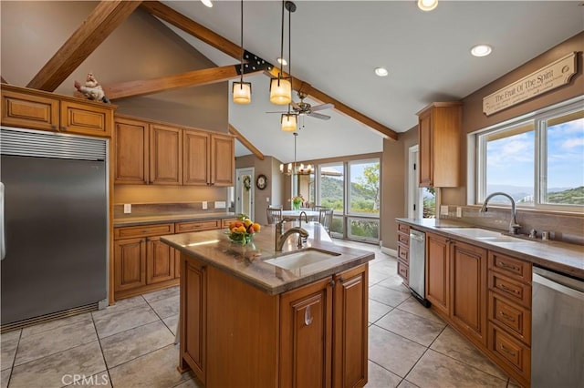 kitchen featuring brown cabinets, stainless steel appliances, a sink, beamed ceiling, and a kitchen island with sink
