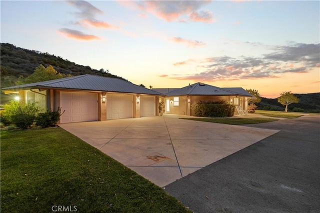 view of front of house with a garage, a lawn, metal roof, and concrete driveway