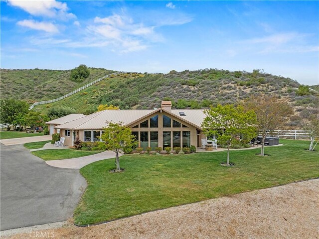 view of front of property featuring fence, driveway, a front lawn, and a chimney