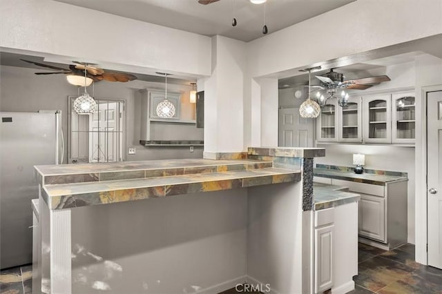 30052 Hunstock St, Castaic, CA 91384 - kitchen featuring a ceiling fan, freestanding refrigerator, glass insert cabinets, dark stone finish floors, and decorative light fixtures