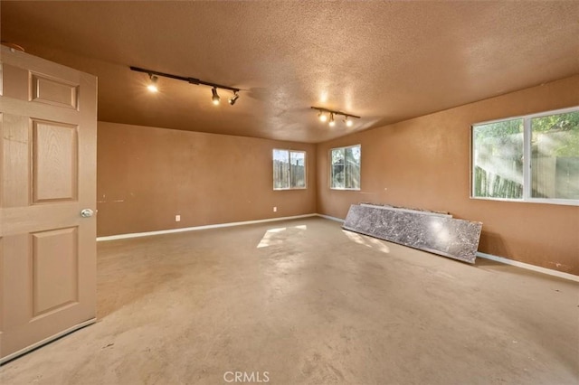 30052 Hunstock St, Castaic, CA 91384 - empty room featuring track lighting, concrete floors, baseboards, plenty of natural light, and a textured ceiling