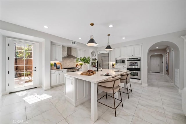 19 Ivanhoe, Irvine, CA 92602 - kitchen with recessed lighting, backsplash, arched walkways, wall chimney exhaust hood, and built in appliances