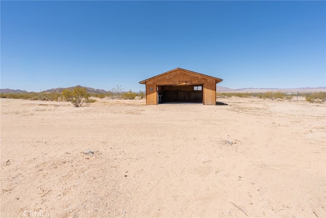 view of yard with a rural view, an outdoor structure, a mountain view, and a garage