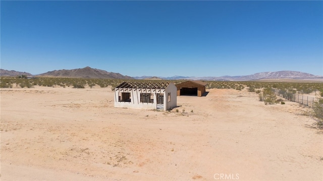 rear view of house with an outdoor structure, a mountain view, and view of desert