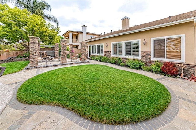 rear view of house with a lawn, stucco siding, and stone siding