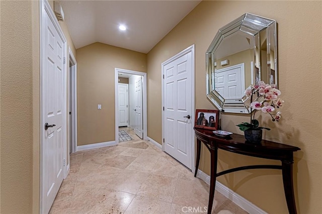 hall with light tile patterned flooring, baseboards, and lofted ceiling