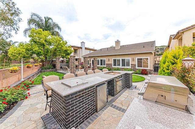 view of patio featuring fence, outdoor wet bar, and area for grilling