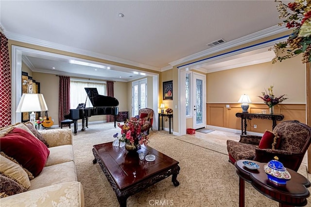 carpeted living area with visible vents, ornamental molding, and a wainscoted wall