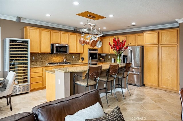 kitchen with crown molding, wine cooler, a kitchen island with sink, light stone counters, and appliances with stainless steel finishes