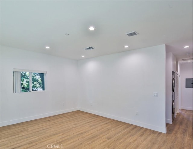 empty room with baseboards, light wood finished floors, visible vents, and recessed lighting