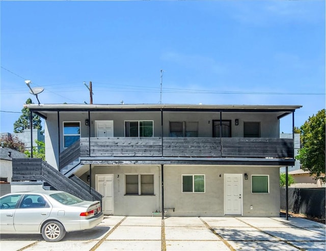 view of front facade featuring fence, stairs, and stucco siding