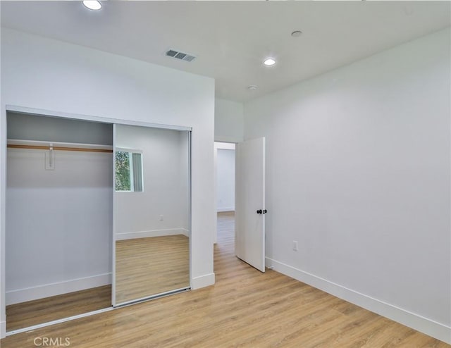unfurnished bedroom with a closet, light wood-style flooring, baseboards, visible vents, and recessed lighting
