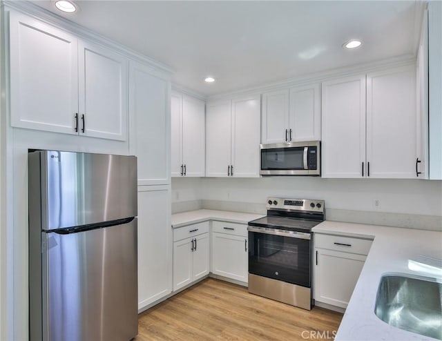 kitchen featuring a sink, stainless steel appliances, light countertops, white cabinets, and recessed lighting