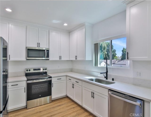 kitchen featuring recessed lighting, white cabinetry, stainless steel appliances, and a sink