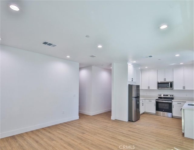kitchen featuring stainless steel appliances, light wood-style flooring, baseboards, visible vents, and light countertops