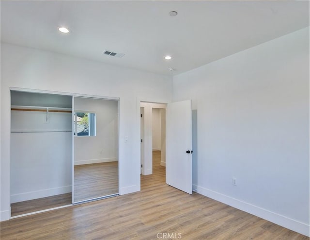 unfurnished bedroom with recessed lighting, wood finished floors, visible vents, a closet, and baseboards