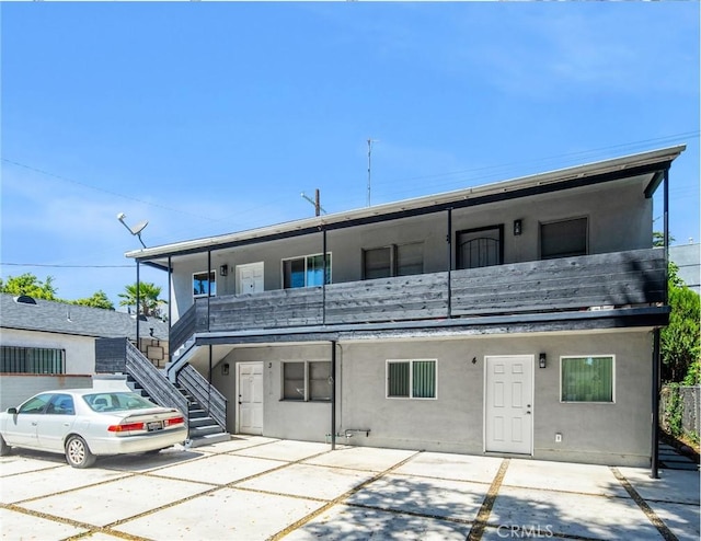 view of front of property with a patio area, stairs, and stucco siding