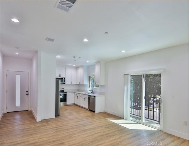 kitchen featuring white cabinets, baseboards, stainless steel appliances, and light wood-type flooring