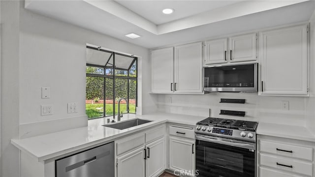 kitchen with appliances with stainless steel finishes, a sink, light countertops, white cabinetry, and recessed lighting