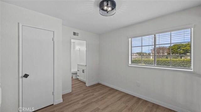 unfurnished bedroom with visible vents, baseboards, ensuite bath, and light wood-type flooring