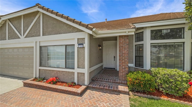 property entrance featuring a garage, stucco siding, a tiled roof, and concrete driveway